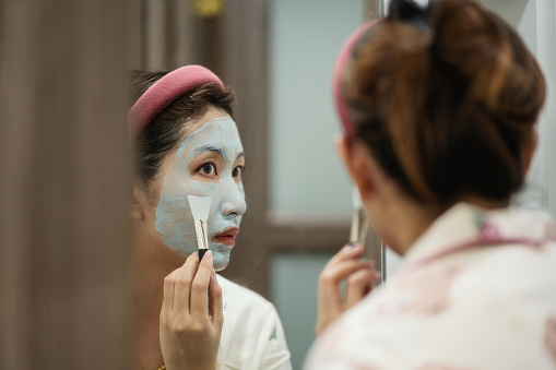 An Asian woman applies facial cleanser on her face，An Asian woman applies facial mask at home
