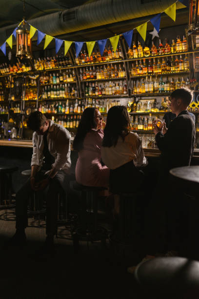 istock Drunk man sits on stool near friends group in Ukrainian bar 2112524040