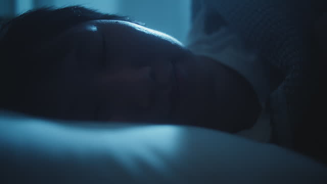 Young Man Sleeping Cozily on a Bed in His Bedroom at Night