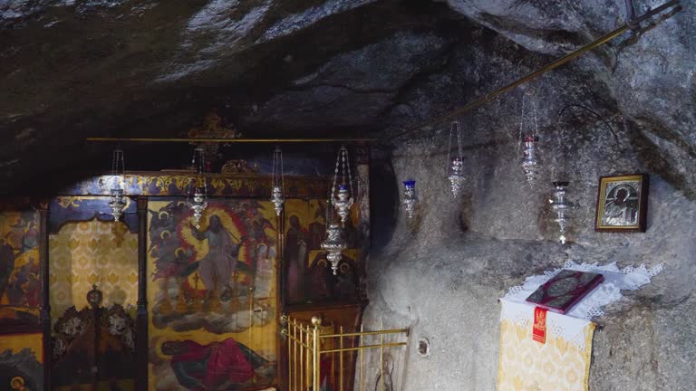 The video presents a church interior with delicate silver chandeliers and a sacred book, all nestled in a cave, the Cave of the Apocalypse, Patmos.