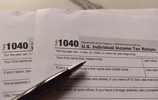 A closeup picture of a Form 1040 on a table with a black pen on it. US tax form.
