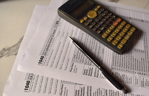 A closeup picture of a Form 1040 on a table with a black pen on it. US tax form.