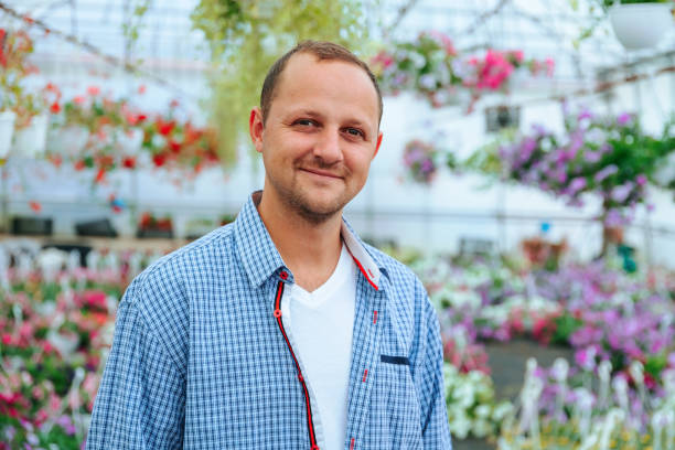 istock A young handsome farmer stands in a greenhouse and looking at camera. 2112555648