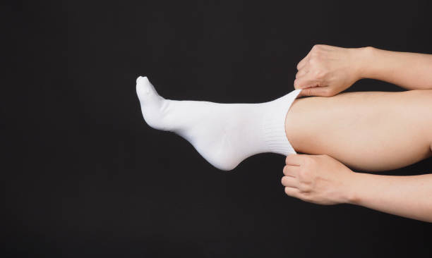 istock Asian Male legs wear white sock and hand is pulling a sock on black background. 2112557251