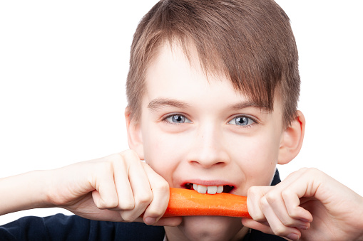 Cute little boy playing whit carrots in the kitchen