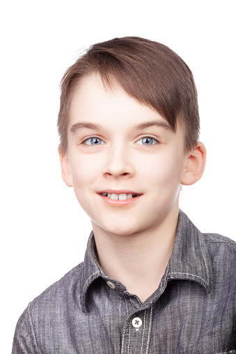 A portrait of cheerful and relaxed young boy with a subtle smile wearing a grey collared shirt. Studio shot against white background