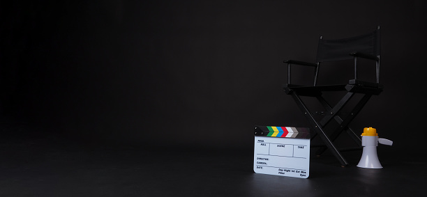 Black director chair and Clapper board with megaphone on black background.