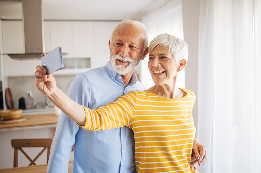 Portrait of happy beautiful senior couple smiling at camera while making selfie