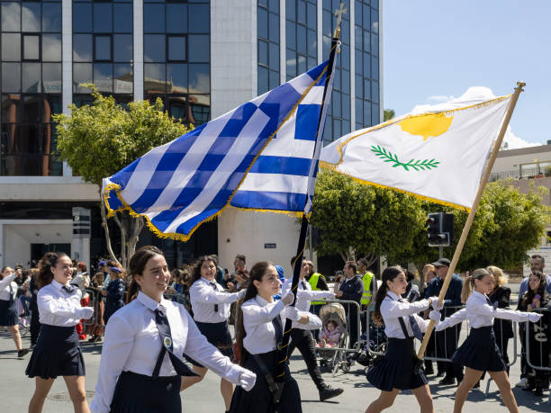 Limassol, Cyprus, March 25th, 2024: Female school students in uniform with Greek and Cypriot national flags marching on Greek Independence Day parade