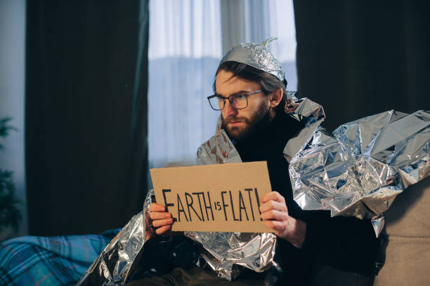 Conspiracy theory, a man wrapped in a foil blanket holds a sign with an inscription. Conspiracy theory, a man wrapped in a foil blanket holds a sign with an inscription. tinfoil barb barbonymus schwanenfeldii stock pictures, royalty-free photos & images