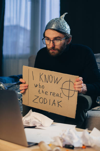 A conspiracy theorist in a tinfoil hat holds a sign in his hands. A conspiracy theorist in a tinfoil hat holds a sign in his hands. tinfoil barb barbonymus schwanenfeldii stock pictures, royalty-free photos & images