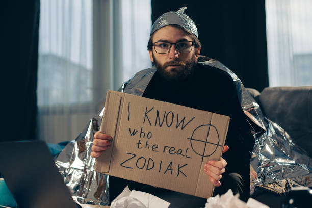 A conspiracy theorist in a tinfoil hat holds a sign in his hands. A conspiracy theorist in a tinfoil hat holds a sign in his hands. tinfoil barb barbonymus schwanenfeldii stock pictures, royalty-free photos & images