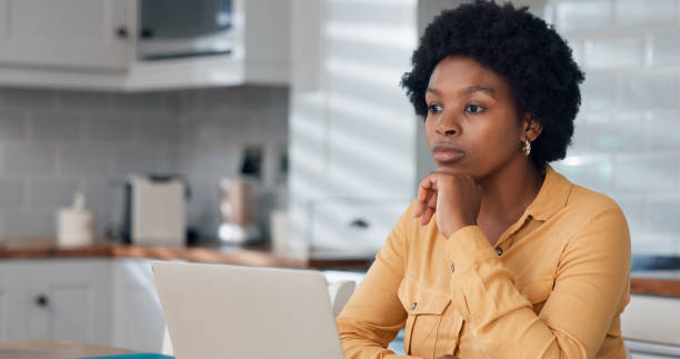 istock Thoughtful serious freelance worker woman working from home kitchen, using laptop, thinking over email letter, online project. Focused student girl studying on internet sitting at computer on table. 2112614044