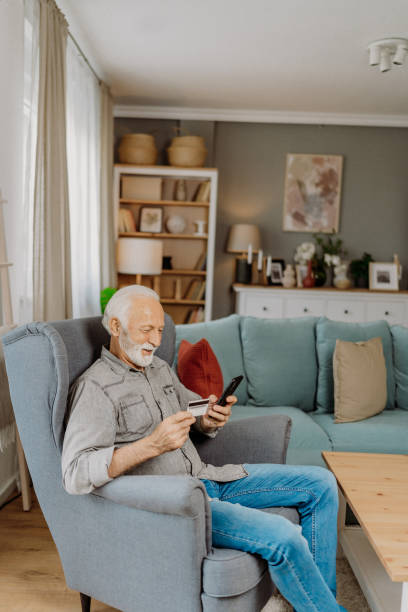istock Senior man using his credit card on the smartphone 2112631681