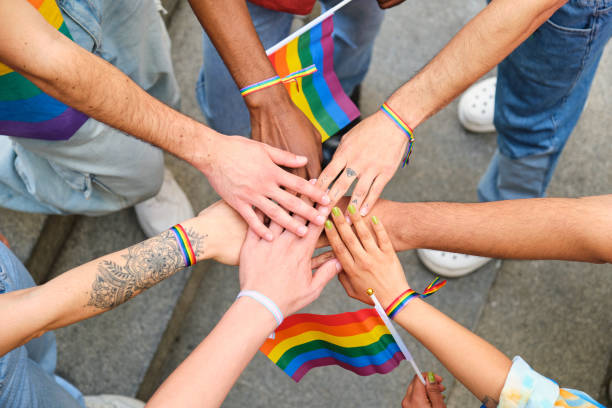 istock A group of people stacking hands and holding rainbow flags. 2112632731