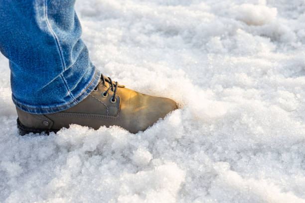 istock a man in boots walks through melted snow. 2112668957