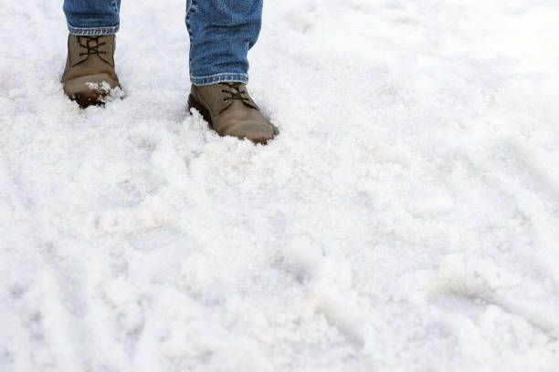 istock a man in boots walks through melted snow 2112670502