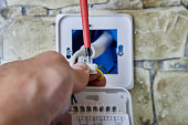 Wiring and installing thermostat for floor heating, electrician connecting wires to terminal uses crosshead screwdriver.