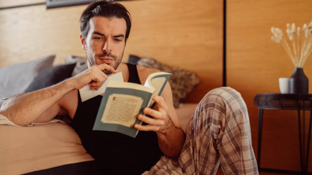 istock Man reading a book in the bedroom 2112685557