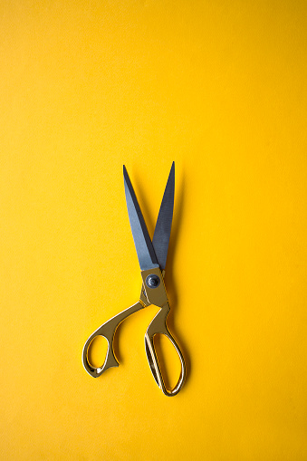 Golden scissors on the yellow background.