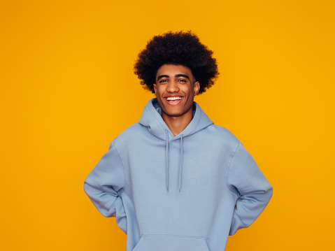 African american man with african hairstyle wearing hoodie standing over isolated yellow background