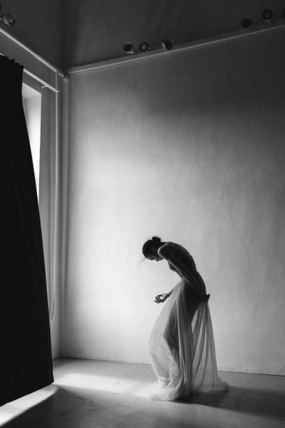 Low Angle View Of Woman Using Mobile Phone While Sitting On Bed In Darkroom