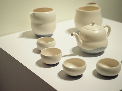 Set of cups and teapot made from white clay displayed at the exhibition