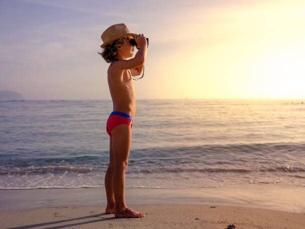 istock Boy observing sea from binoculars at sunset 2112754496