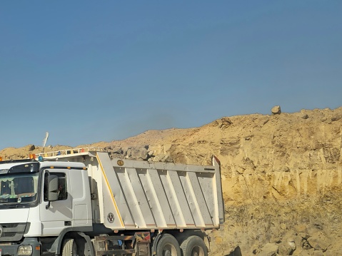 Cairo, Egypt, March 23 2024: Lorry at a construction and working site in the desert in the process of developing new roads and widening roads in Egypt as new real estate projects, selective focus