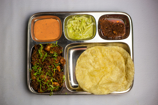 Chicken Masala chaap with Lucchi, chuntney, sauce and chilli dip served in thali platter isolated on background top view of bangladeshi food set menu