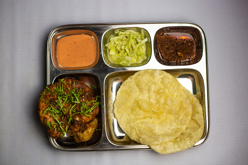 Chicken chaap with Lucchi, chuntney, sauce and chilli dip served in thali platter isolated on background top view of bangladeshi food set menu