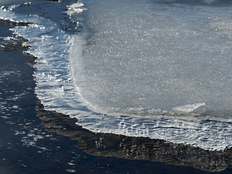 Ice formations on water's edge in sunlight