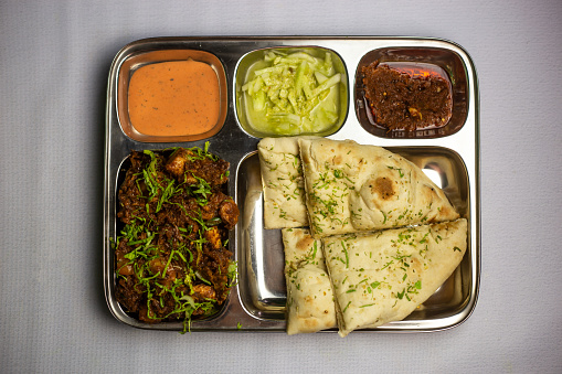 Chicken Masala chaap with garlic nan, chuntney, sauce and chilli dip served in thali platter isolated on background top view of bangladeshi food set menu