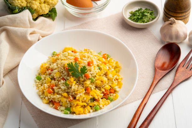 istock Cauliflower fried rice,Stir fried cauliflower rice with eggs ,carrot ,bean and corn in white plate. 2112780469