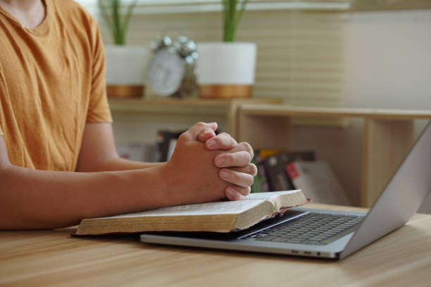 istock A mature man praying, after doing some personal bible study, in a room. 2112801348