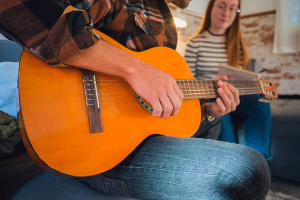 istock Man and woman sitting on a couch with a guitar 2112848215