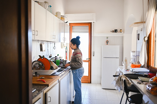 Side view portrait of a woman cleaning dirty dishes.