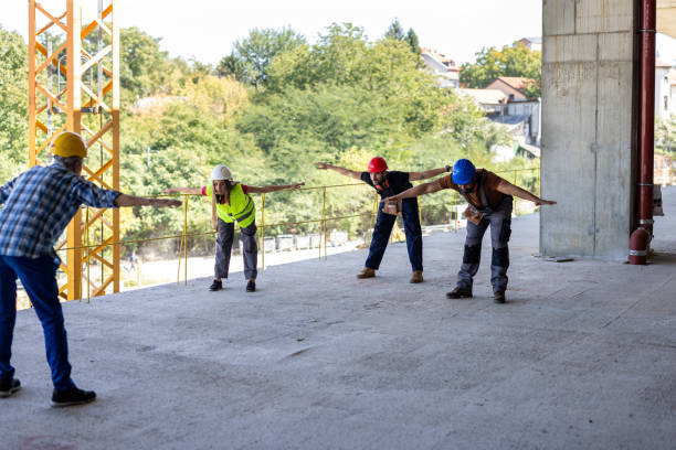 istock Four Workers of Different Ethnicities are Exercising at the Building Site. 2112885076