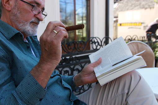 Side view close up of brutal harsh professional investor, shareholder smoking cigar over gray background