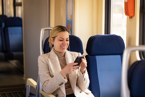 Young business woman looking at phone screen while traveling in a train