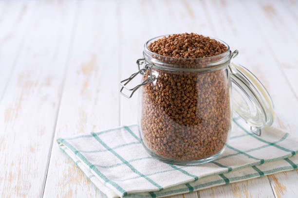 istock Raw buckwheat in glass storage jar on a white wooden table. 2112913234