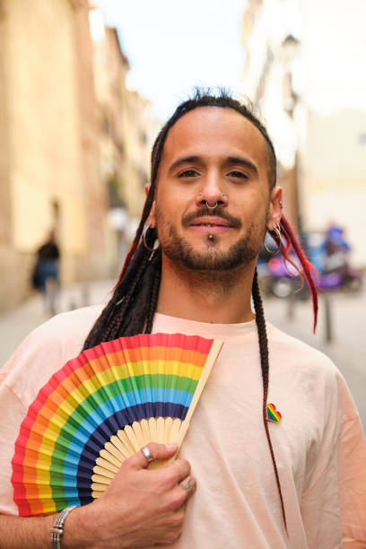istock Gay man with a rainbow fan smiling and looking at camera. 2112935182