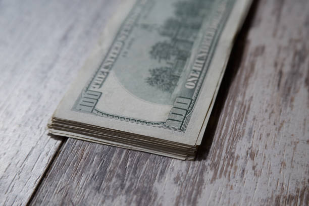 istock A stack of hundred-dollar bills on a wooden table close-up 2113004799