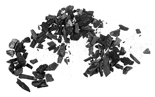Natural wooden charcoal pieces isolated on a white background, top view. Black charcoal particles.