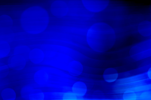 Abstract wavy background in blue tones with defocused bokeh light.