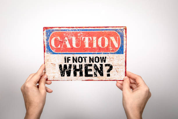 istock If Not Now When? Metal warning sign in a woman's hand on a white background 2113097346