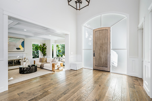 A 1930s American Tudor Revival Style Real Estate Interior Living Room and dining in the mid-west of United States for sale. The empty vacant property featuring built-in woodwork shelving, double French doors and staircase to second floor, oak hardwood flooring.