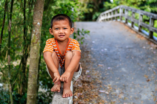 Vietnamese little boy sitting on the bridge, South Vietnam