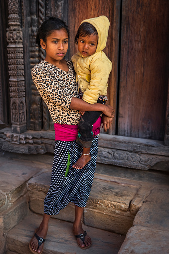 Nepali girls holding her little brother on the Durbar Square of Bhaktapur. Bhaktapur is an ancient town in the Kathmandu Valley and is listed as a World Heritage Site by UNESCO for its rich culture, temples, and wood, metal and stone artwork.