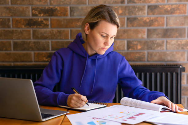 istock A woman in a blue sweater is working at a desk, writing notes in a notebook, reading a book 2113143254